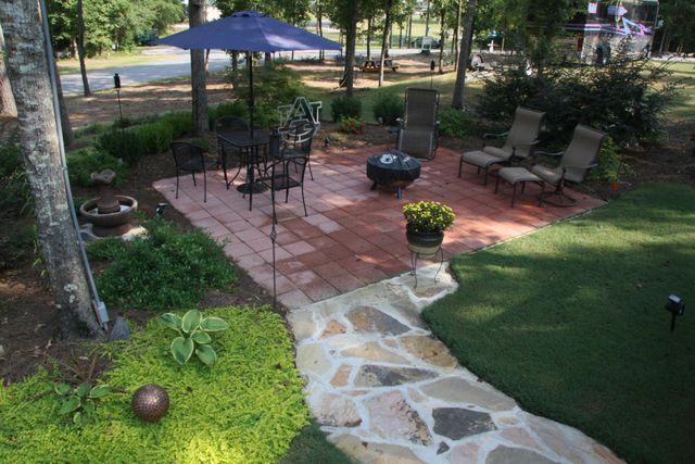 A landscaped lot with a stone path, patio, umbrella table and fire pit