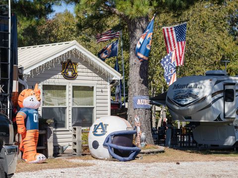 A small cottage decorated for Auburn, with a tiger mascot, an AU helmet and flags beside an RV