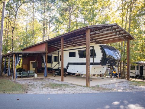 An RV site with a covered carport under tall pines