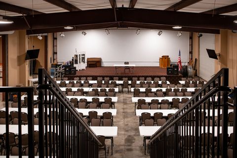 The clubhouse and event center set up with rows of tables and chairs, a staircase and balcony at the back