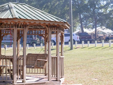A wooden gazebo with a porch swing on the lawn at University Station