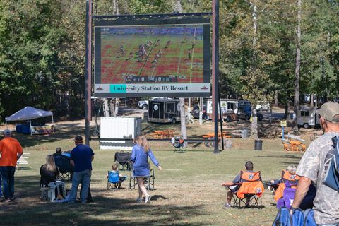 Guests in lawn chairs watching a game on the outdoor Jumbotron screen