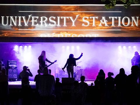 A band on the University Station stage under purple lights, with the crowd in silhouette
