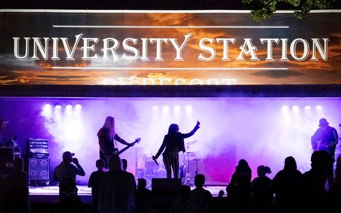 A band on the University Station stage under purple lights, with the crowd in silhouette