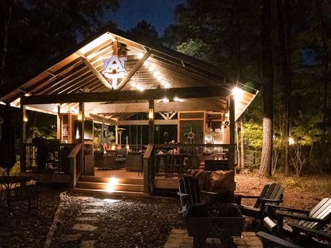 A timber pavilion glowing warmly at night among the pines, with lounge chairs in front