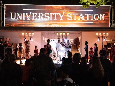The University Station stage lit up at night with a crowd gathered in front for the Halloween weekend show