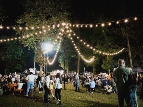 Guests on the lawn under strings of lights at night at University Station