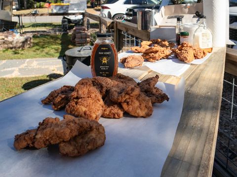 Fried chicken and a jar of honey on a tailgate counter
